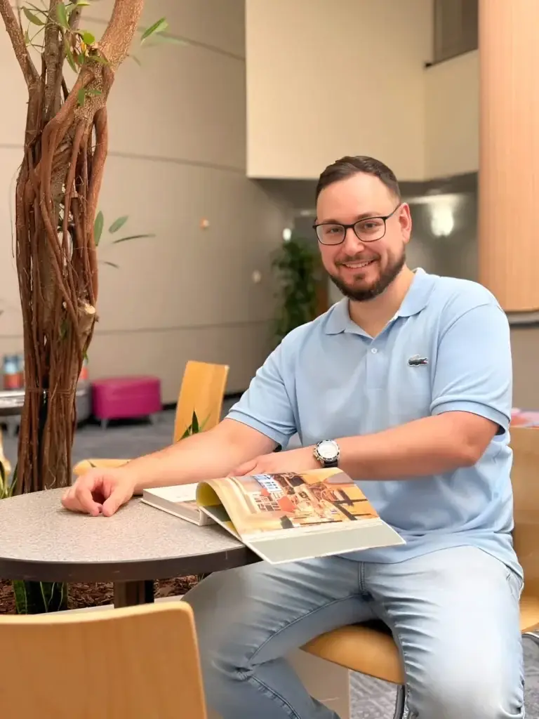 Professor da Marques School of English sorrindo enquanto folheia um livro do curso